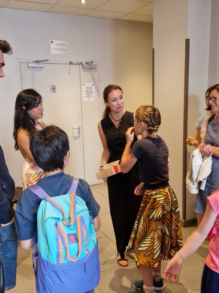 Groupe de parent et enfant qui donne un cadeau a une jeune femme qui les remercie et qui est souriante
