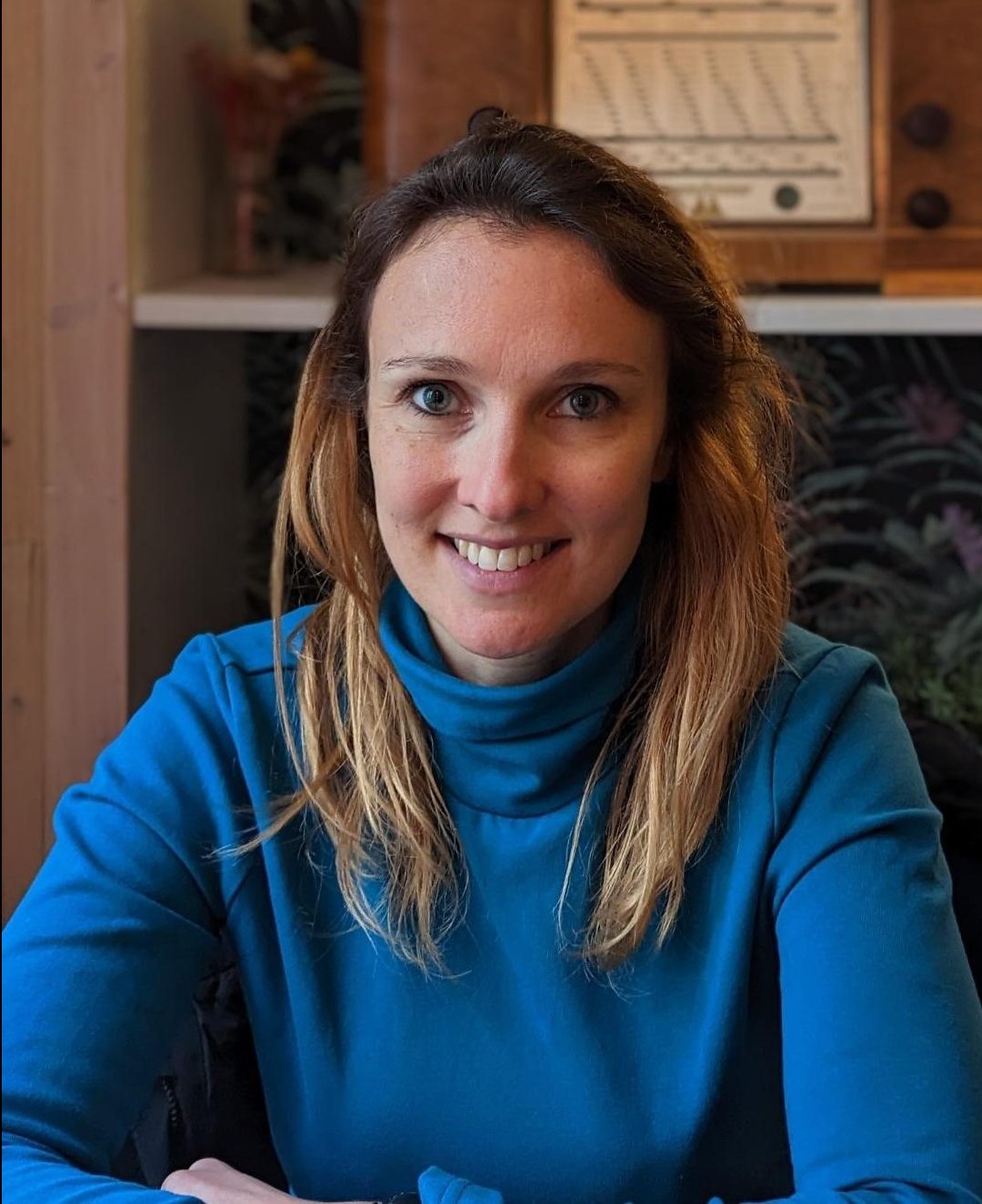 portrait d'une femme souriante habiller avec un col roulé bleu, les cheveux lisse (comedienne et professeure de theatre)