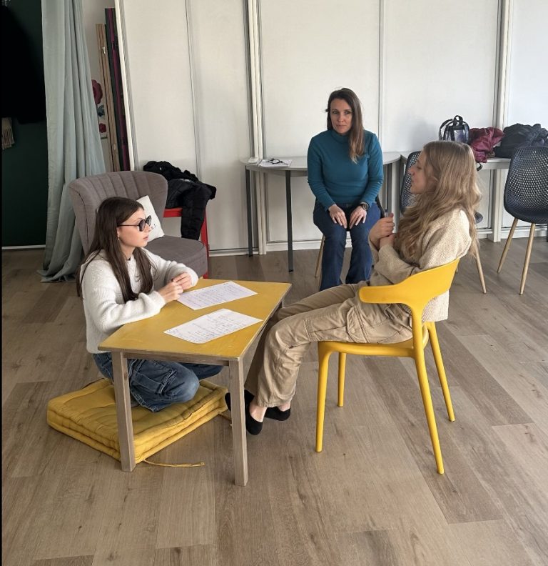 femme sur une chaise avec deux petite fille (enfant) devant la femme et recite un texte
